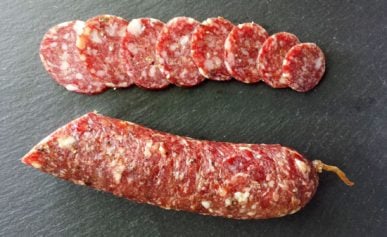 Slices of fennel salami on a piece of slate.