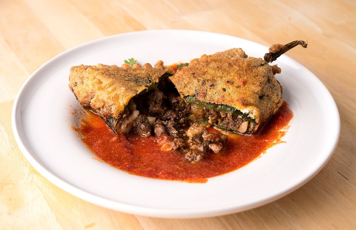 A broken open chile poblano rellenos on a plate