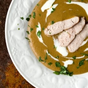 A bowl of acorn soup with slices of grouse.