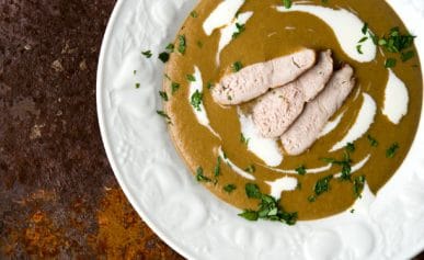 A bowl of acorn soup with slices of grouse.