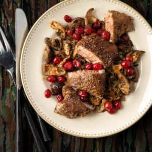 Grouse breast with mushrooms and cranberries on a plate.