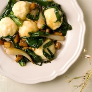 Ricotta gnudi on a plate with onions and mushrooms