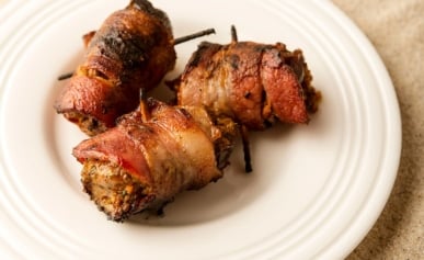 Three bacon wrapped dove breasts on a plate.