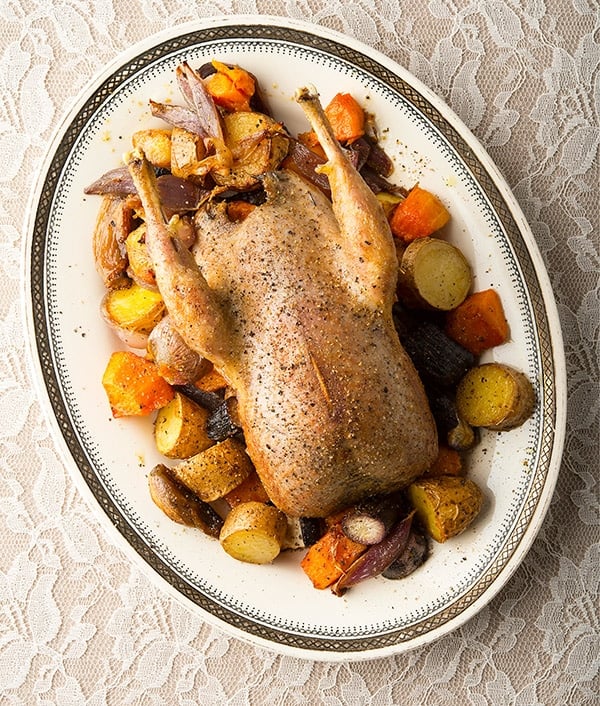 Roast sharp-tailed grouse with root vegetables on a platter