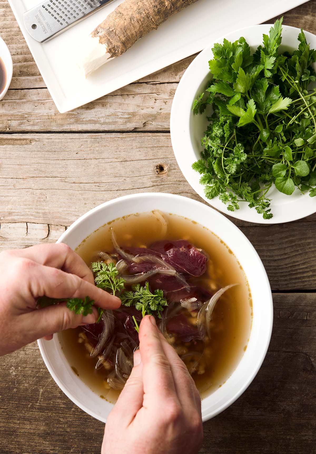 Adding herbs to a bowl of goose soup. 