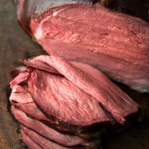 Slices of smoked venison roast on a cutting board.