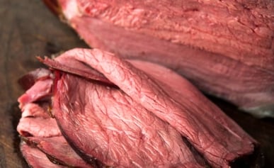 Slices of smoked venison roast on a cutting board.