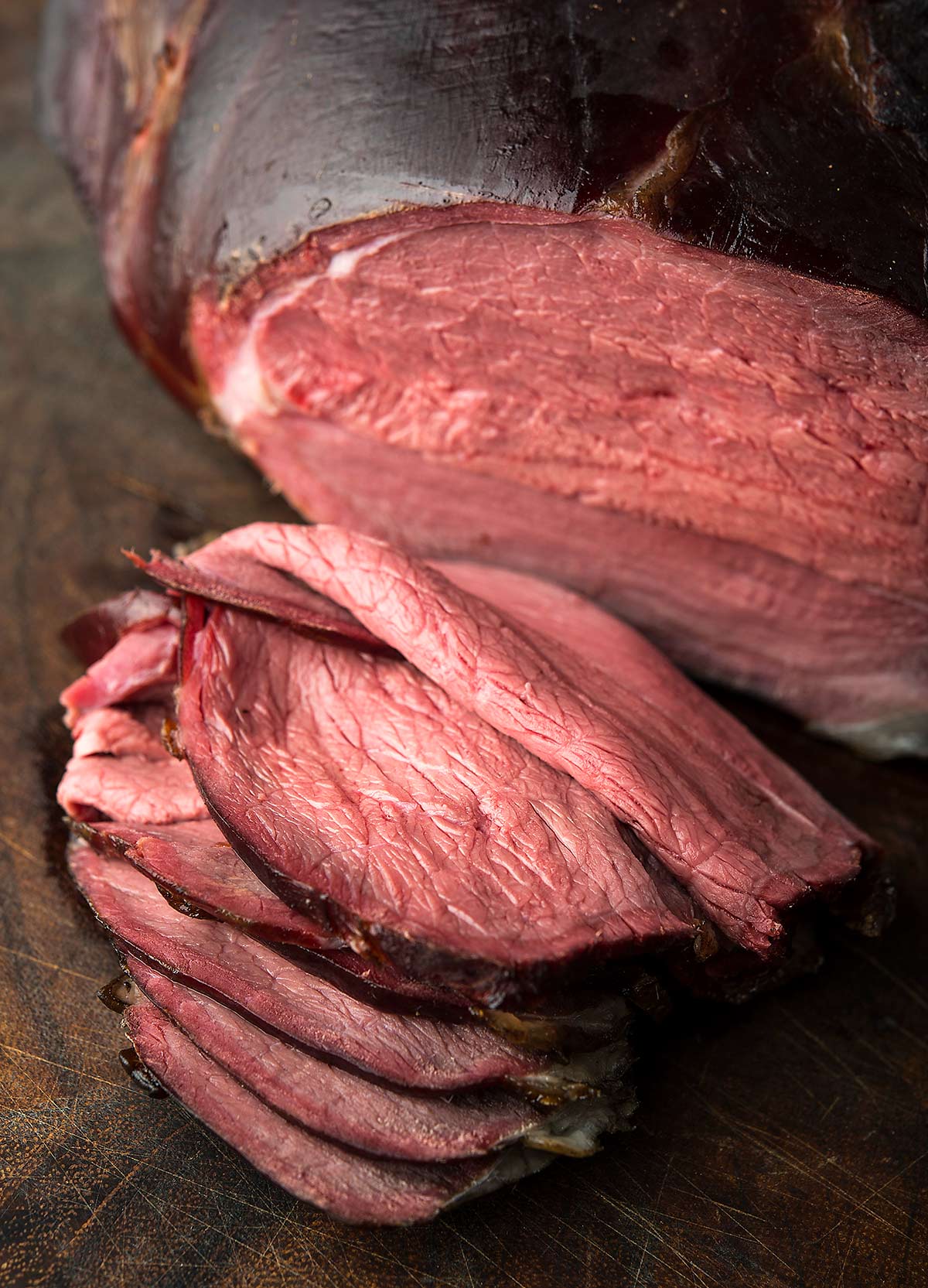 Slices of smoked venison roast on a cutting board. 