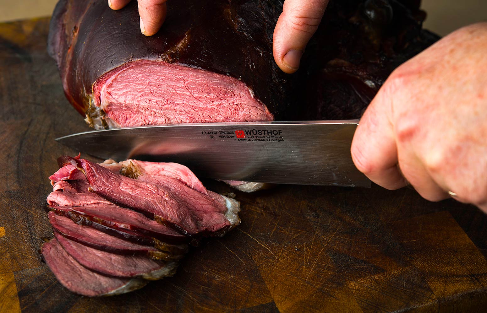 Slicing smoked venison on a cutting board. 