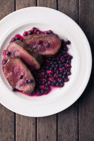 pickled blueberries with venison steak on a plate