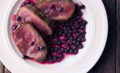 pickled blueberries with venison steak on a plate
