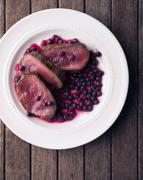 pickled blueberries with venison steak on a plate