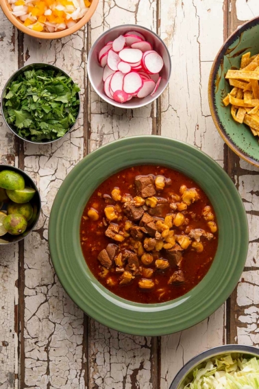 pozole rojo in a bowl with all the fixins