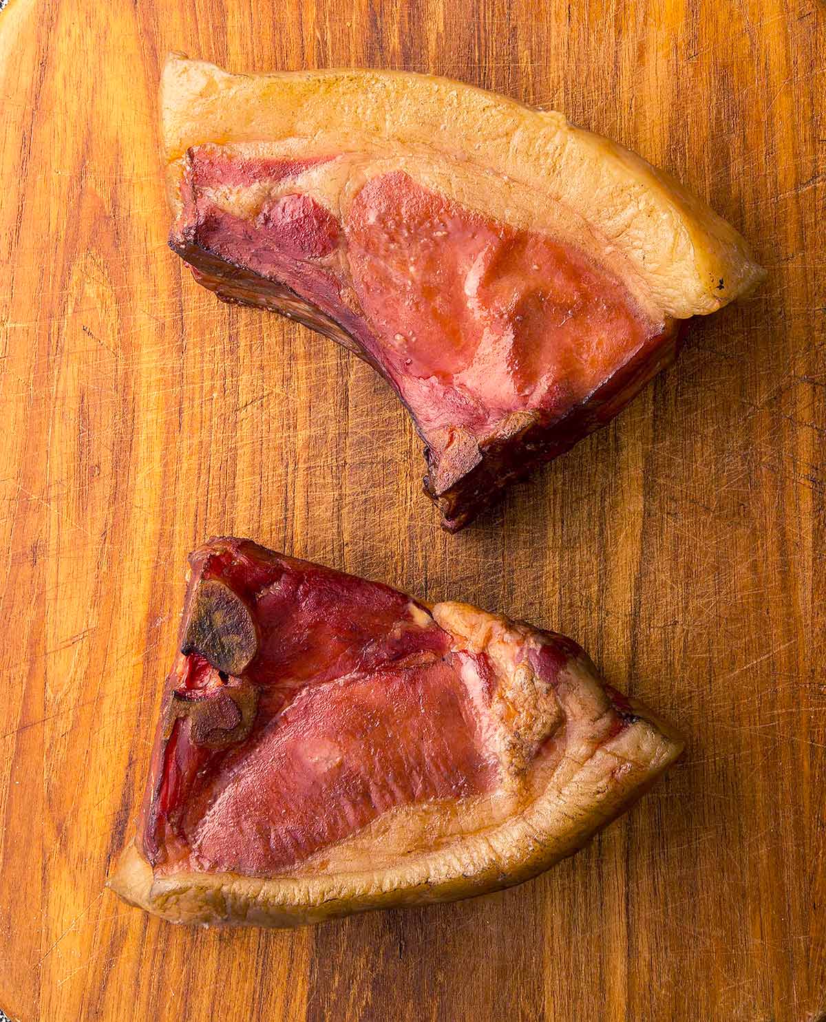 A pair of smoked pork chops on a cutting board.