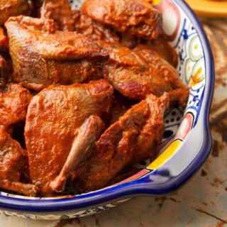 A bowl of smoked doves with guajillo sauce.