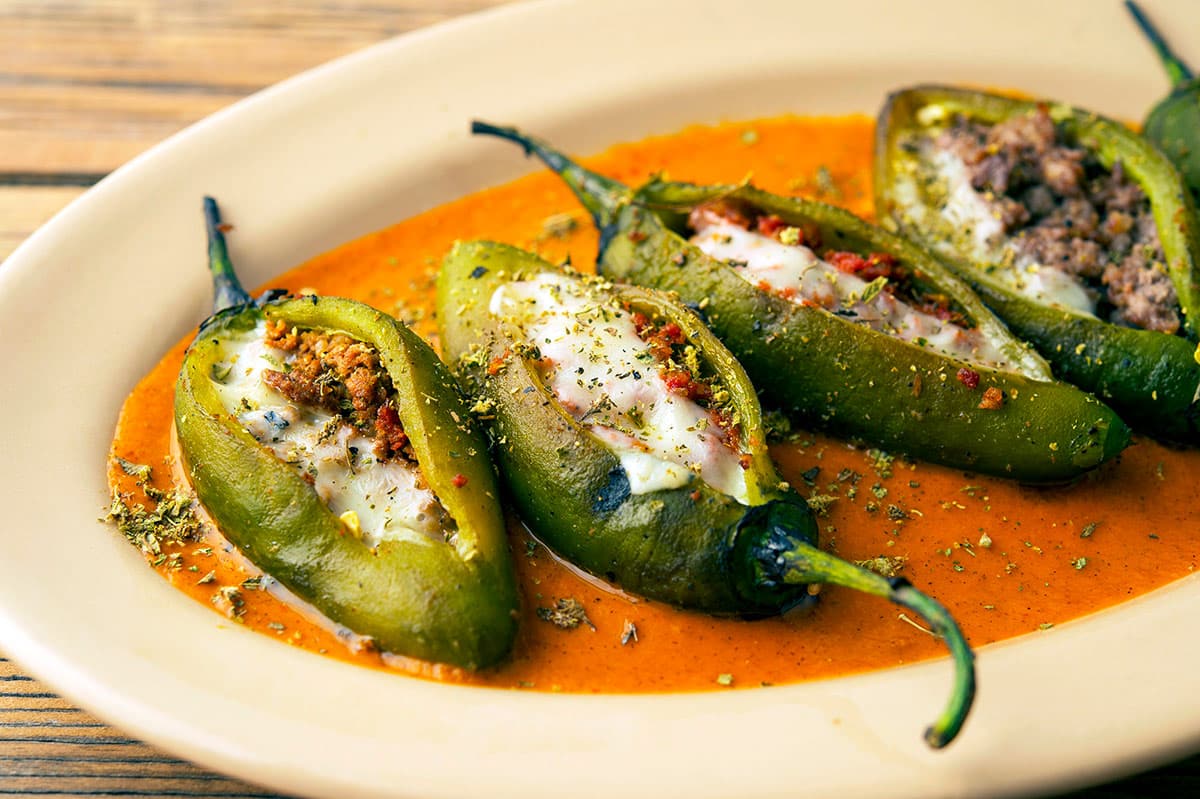 Close up of a platter of sausage stuffed jalapenos. 