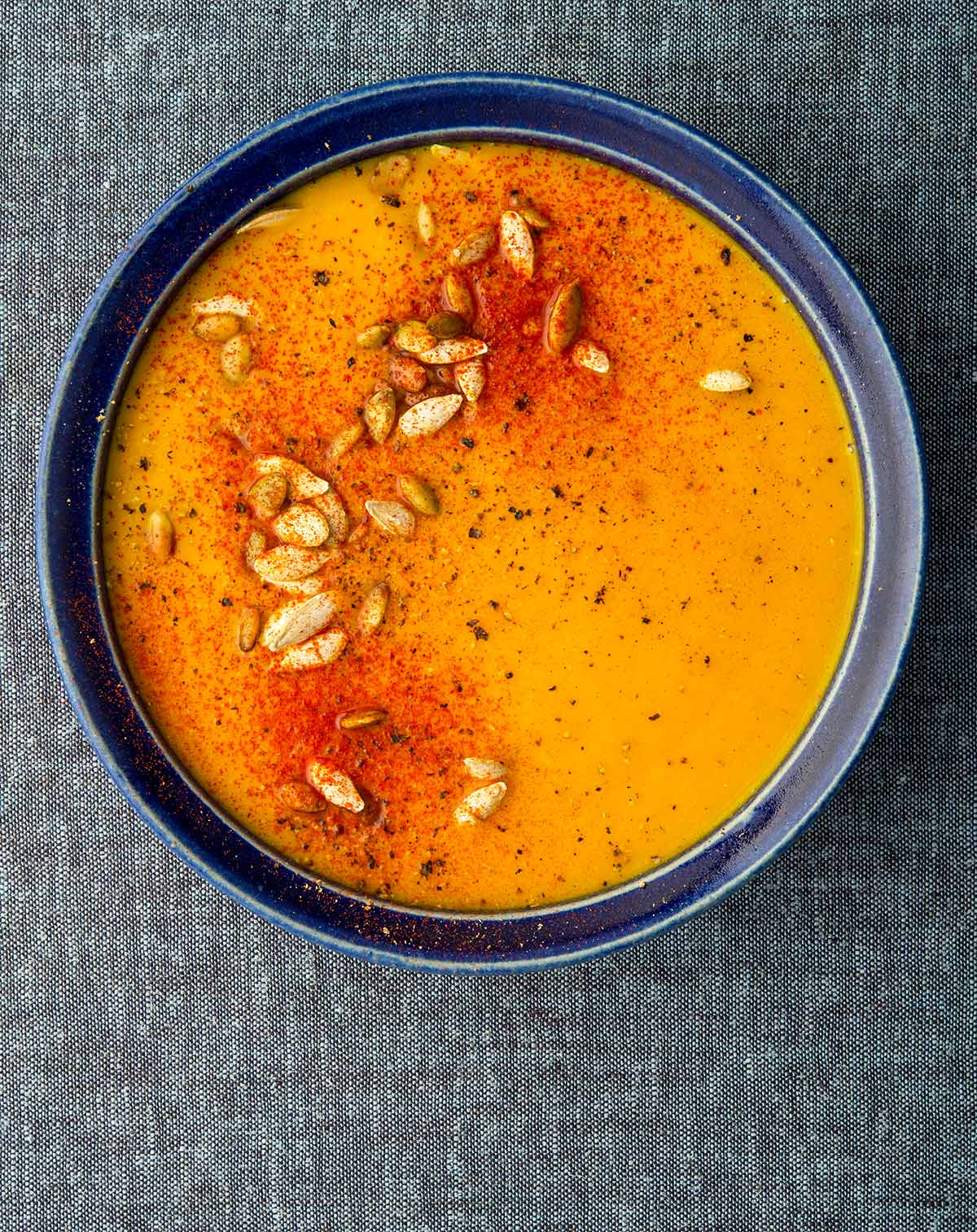 A bowl of spicy butternut squash soup, garnished with squash seeds.