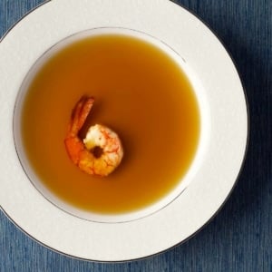 A bowl of shrimp stock with one shrimp in it