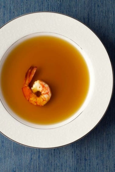 A bowl of shrimp stock with one shrimp in it