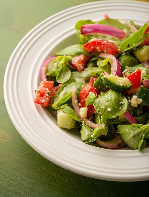 een bord posteleinsalade met komkommers en tomaten.