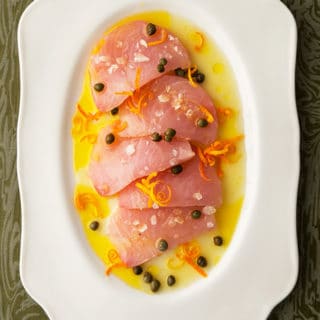 Slices of tuna crudo on a platter