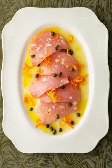Slices of tuna crudo on a platter