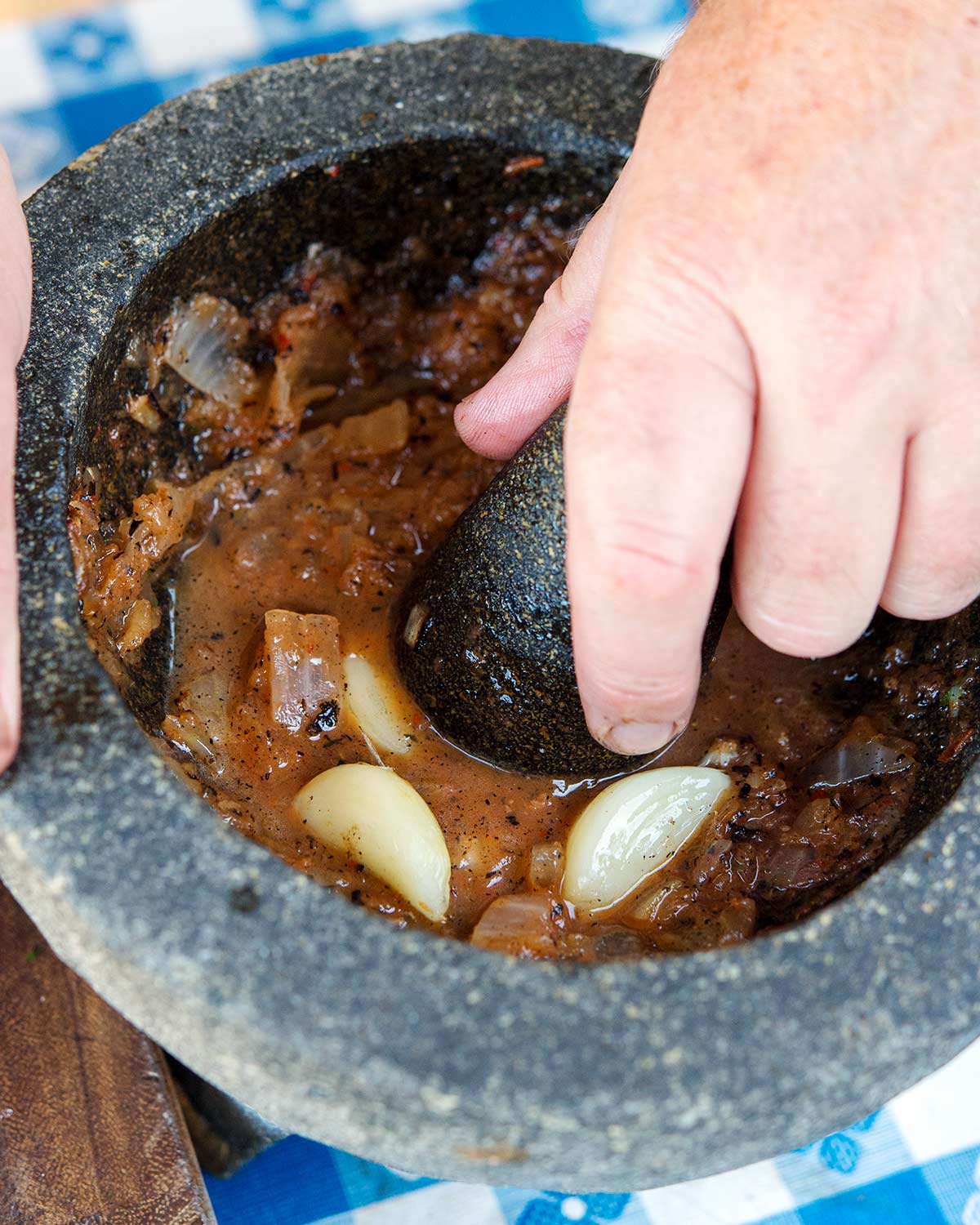 Grinding the roasted salsa in a molcajete