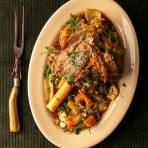 Greek lamb shanks with braised vegetables on a platter.