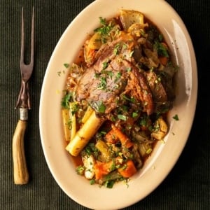 The finished Greek lamb shank on a platter with root vegetables