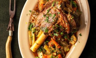 The finished Greek lamb shank on a platter with root vegetables