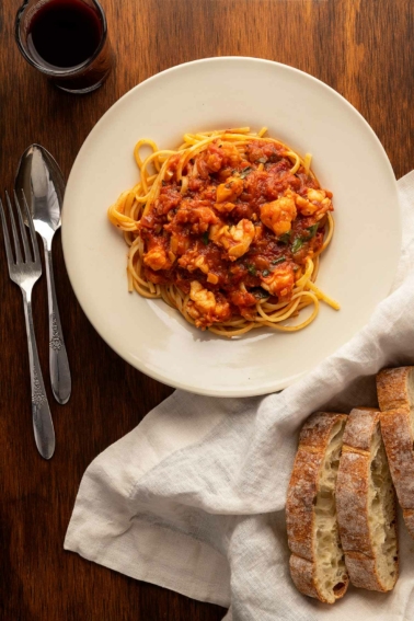 lobster fra diavolo with pasta and bread on a plate.