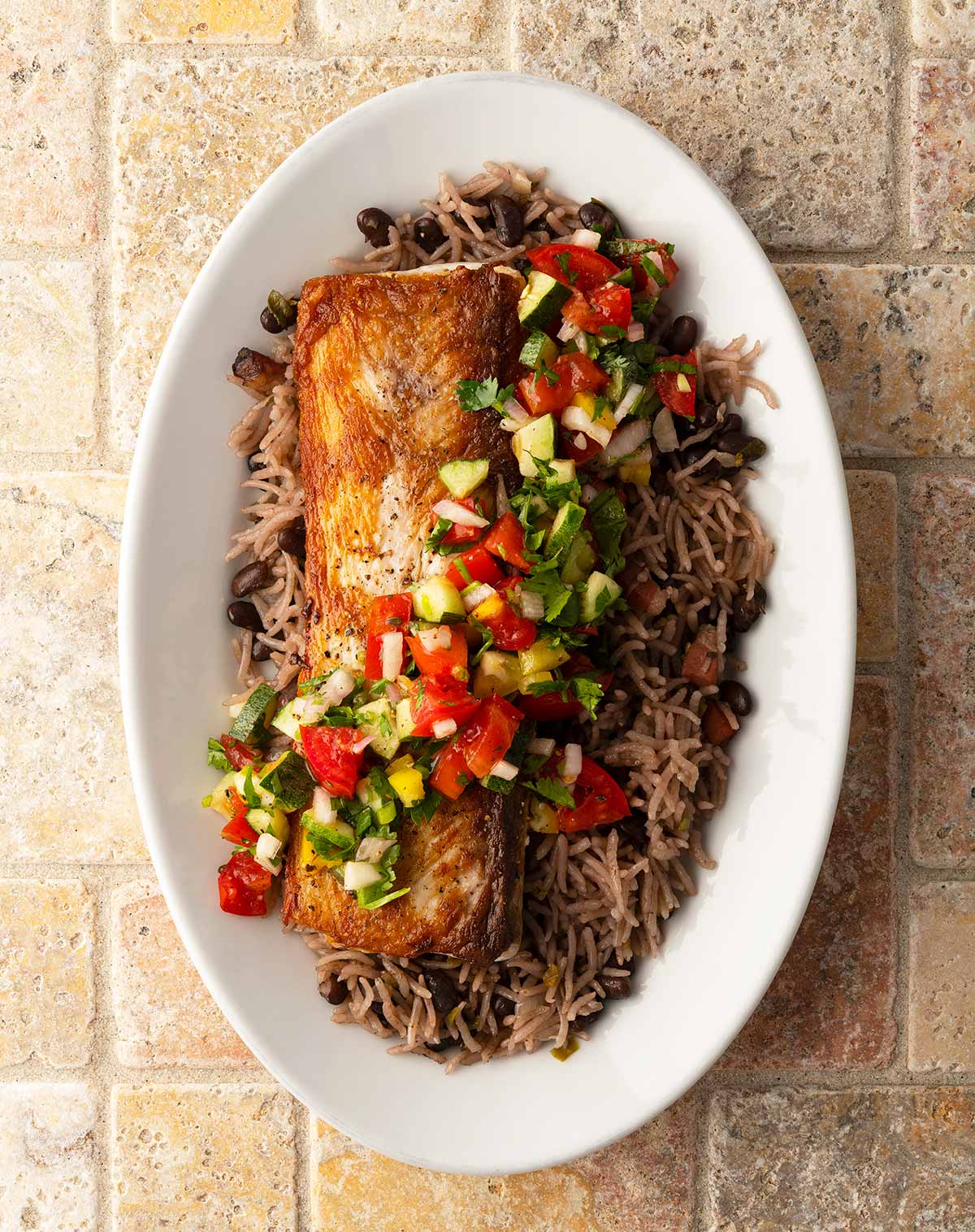 A plate of pan seared mahi mahi with rice and salsa