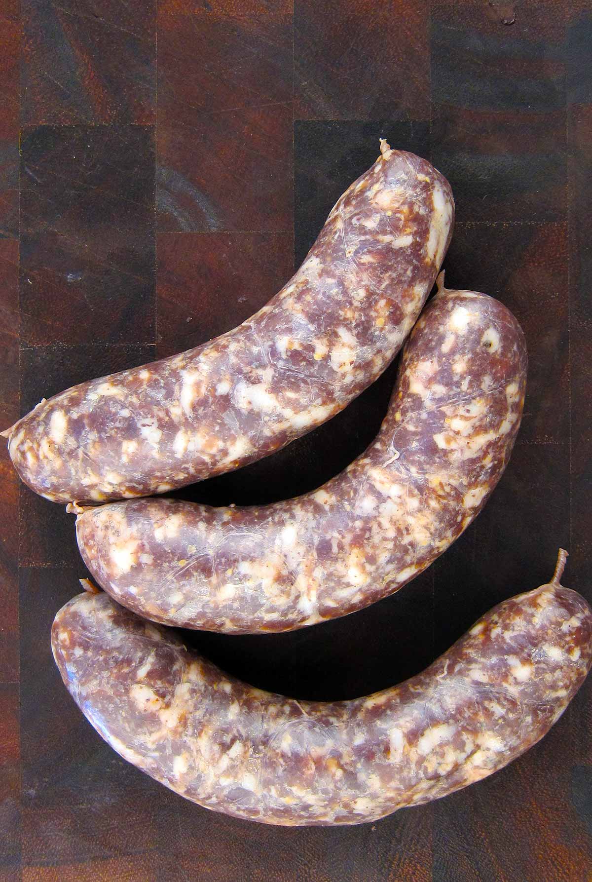 Three venison bratwurst on a cutting board