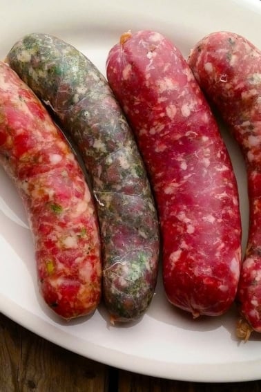 Four varieties of fresh, homemade sausages on a plate