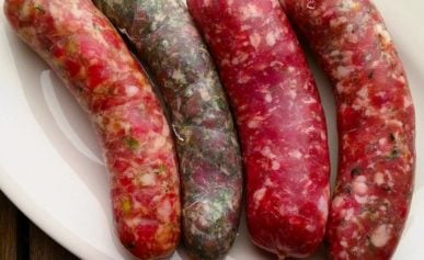 Four varieties of fresh, homemade sausages on a plate