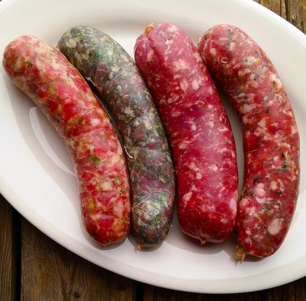 Four varieties of fresh, homemade sausages on a plate