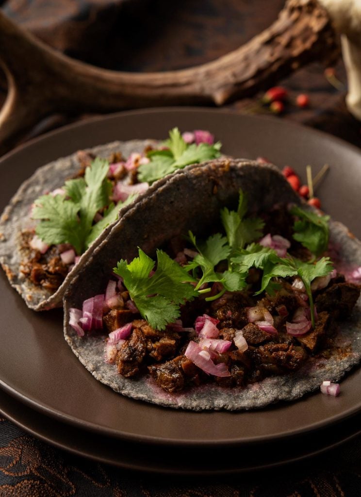 Two tacos filled with recado negro picadillo. 