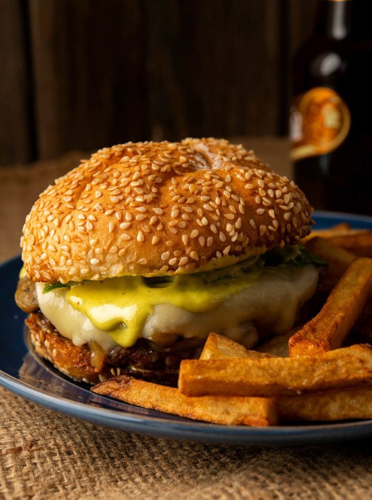 A duck burger on a plate with duck fat fries. 