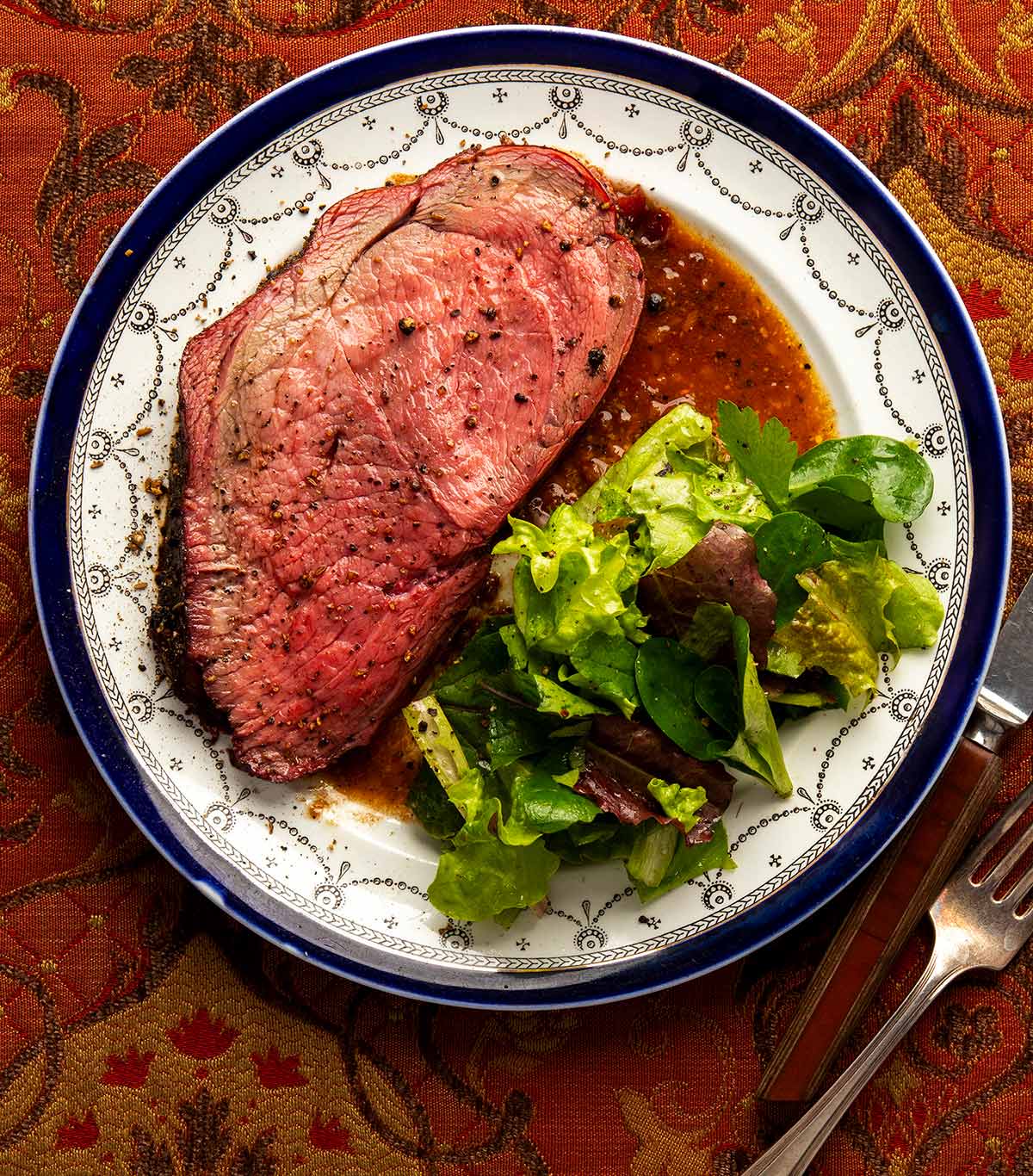 A slice of elk roast on a plate with a salad.