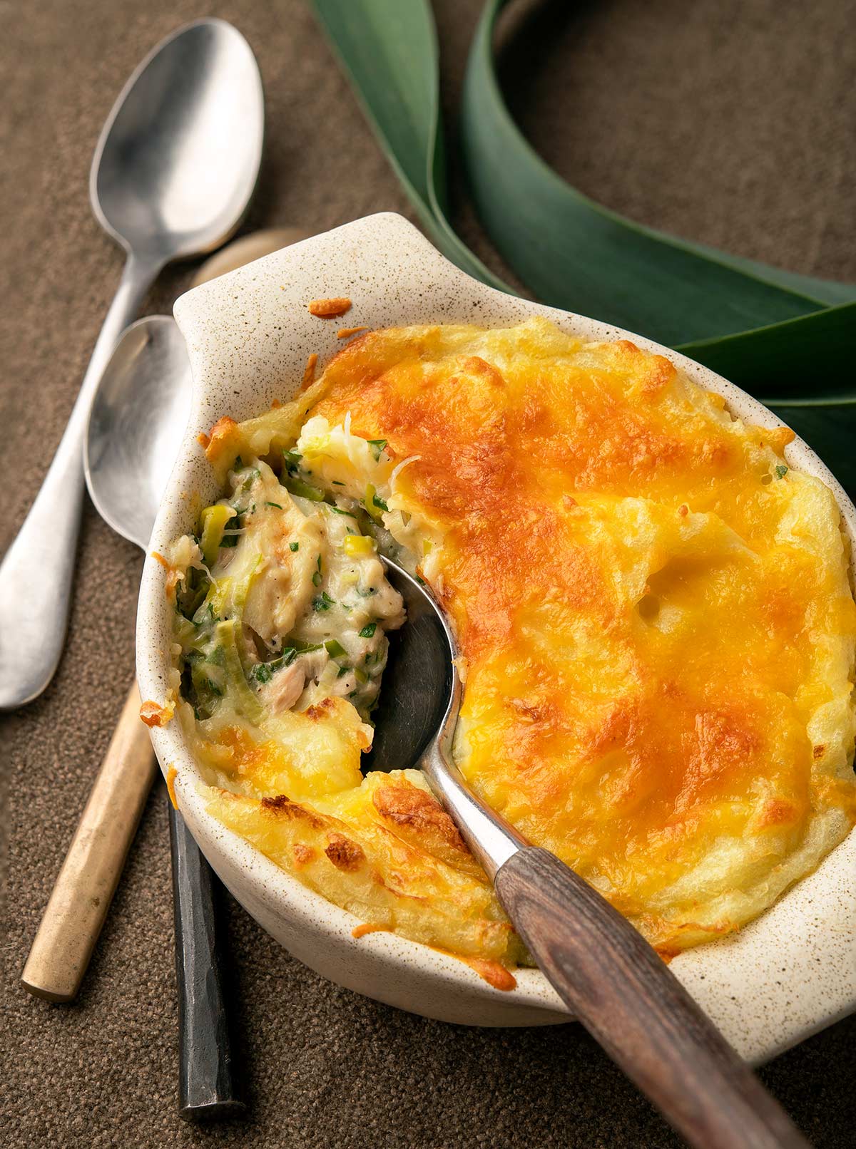 Spooning out some fish pie with leeks out of the casserole. 