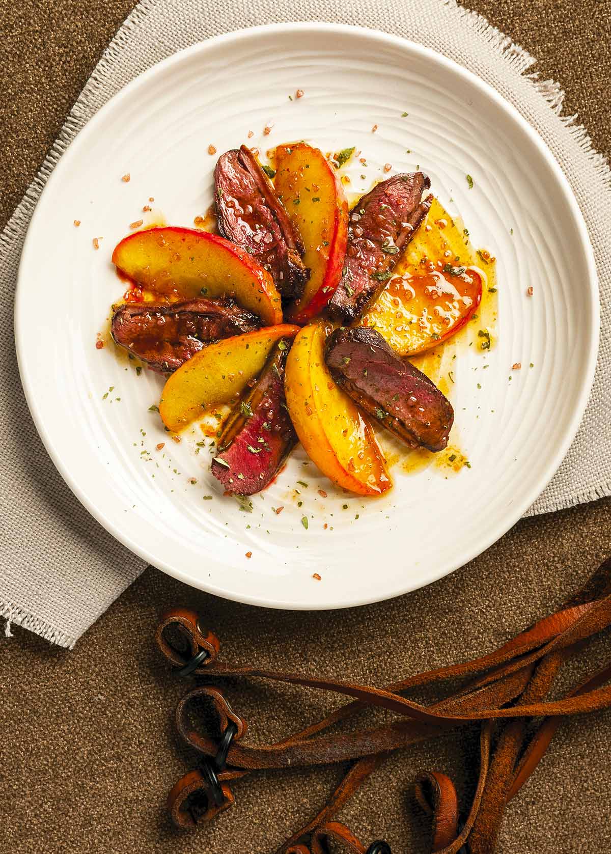 A plate of duck with apples with a duck lanyard in the background. 