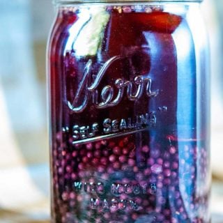 A jar with alcohol and elderberries for elderberry liqueur.