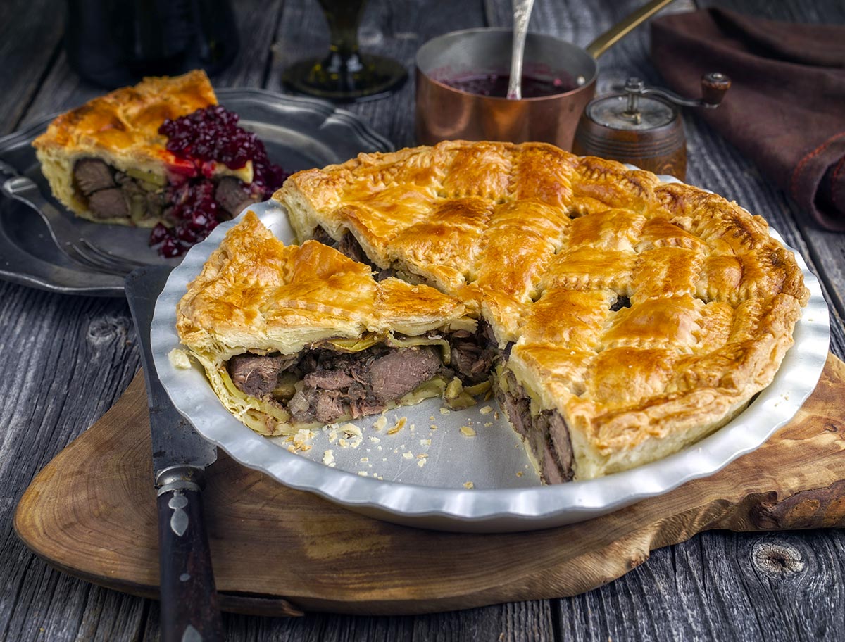 A British duck pie on a platter with a piece removed. 