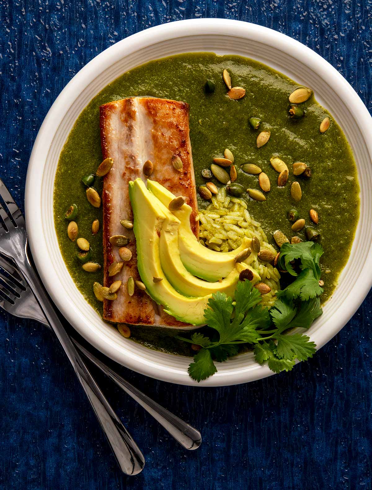 Dorado fish with cilantro sauce on a plate with avocado and rice. 