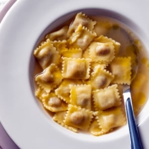 Duck ravioli in broth in a bowl.