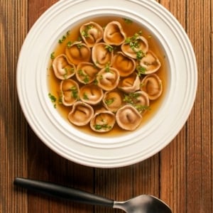 A bowl of cappelletti pasta swimming in duck stock.