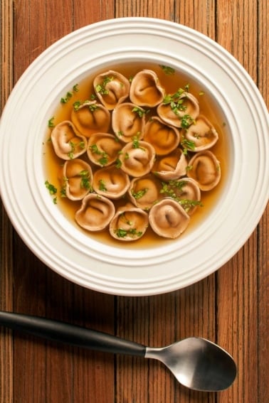A bowl of cappelletti pasta swimming in duck stock.
