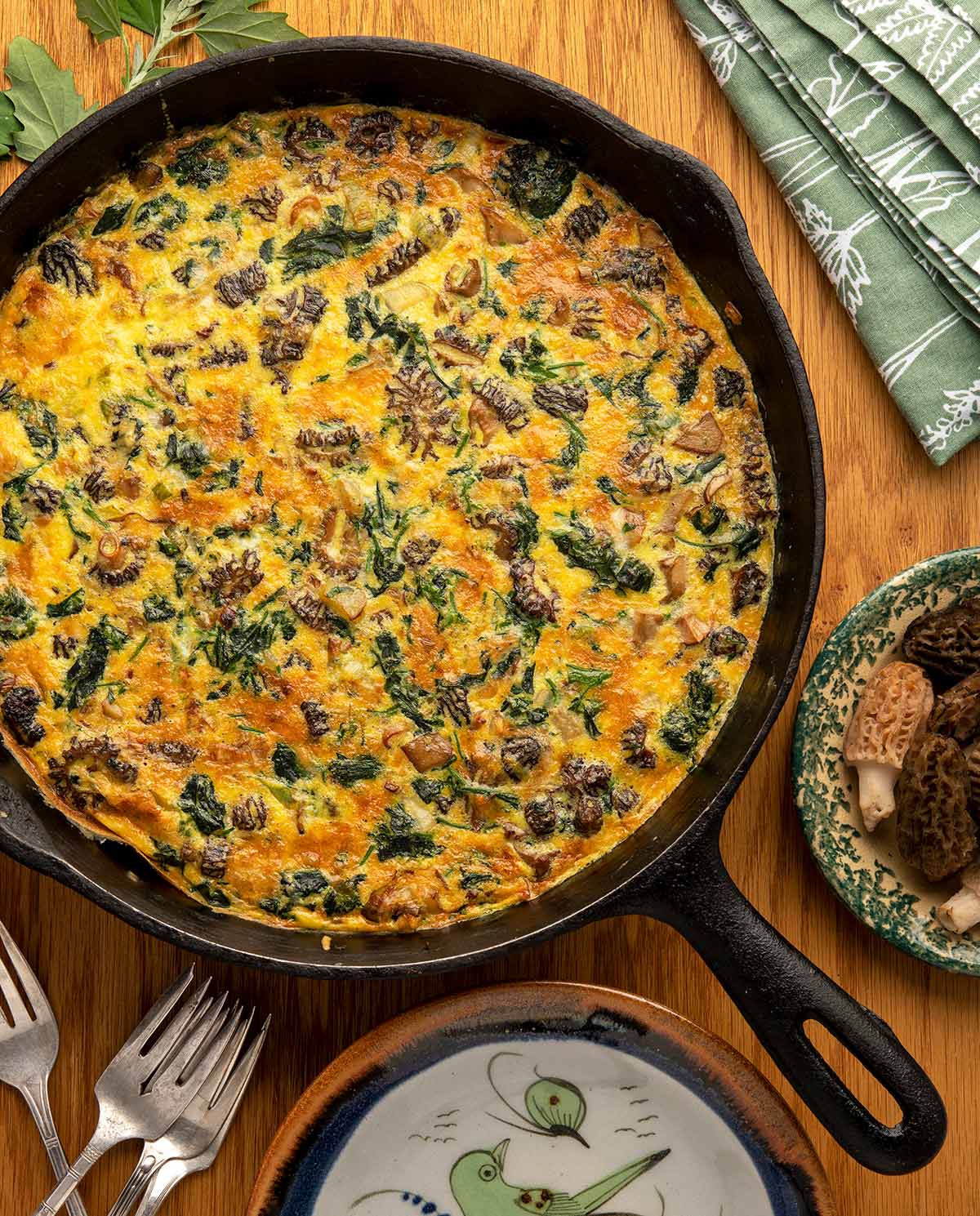 Close up of mushroom spinach frittata in a cast iron pan on a table. 
