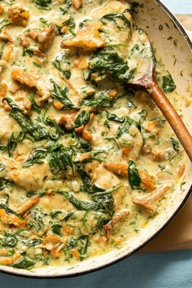 Pheasant with mushrooms, cream and greens in a pot.
