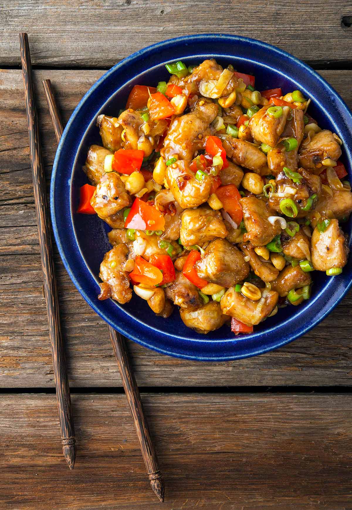 A bowl of kung pao pheasant stir fry, with chopsticks. 